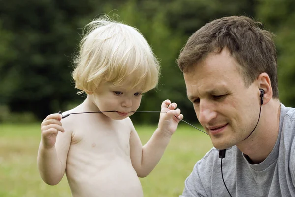 O filho com o pai brinca com fones de ouvido — Fotografia de Stock