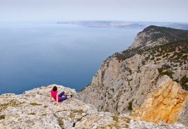 uçurumun üstünde deniz üzerinde oturan kız