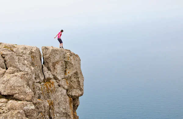 Lonely woman standing on the edge of the cliff — Stock Photo, Image