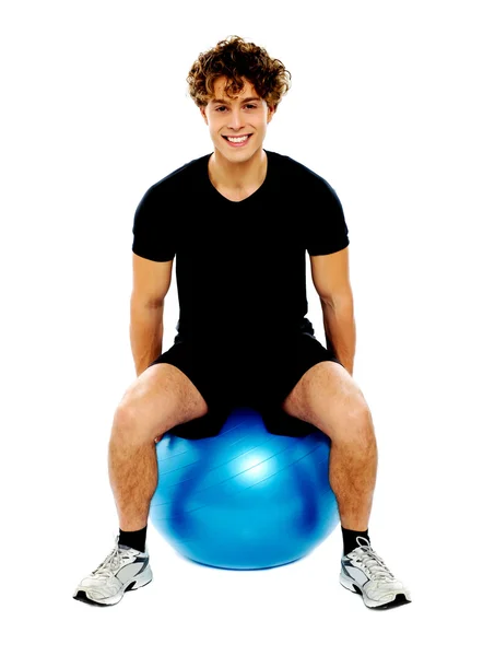 Красавчик, сидящий на мяче для упражнений — стоковое фото