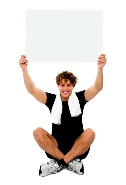 Guapo atleta sosteniendo cartel en blanco — Foto de Stock