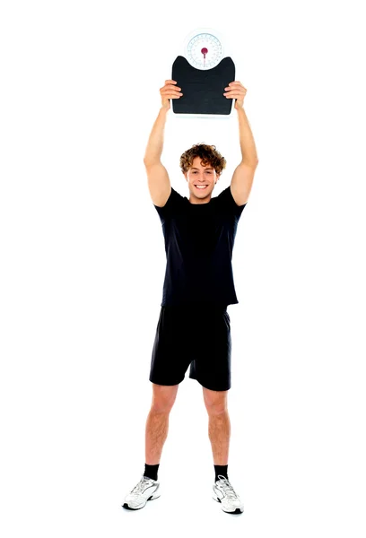 Male athlete holding weighing machine over his head — Stock Photo, Image