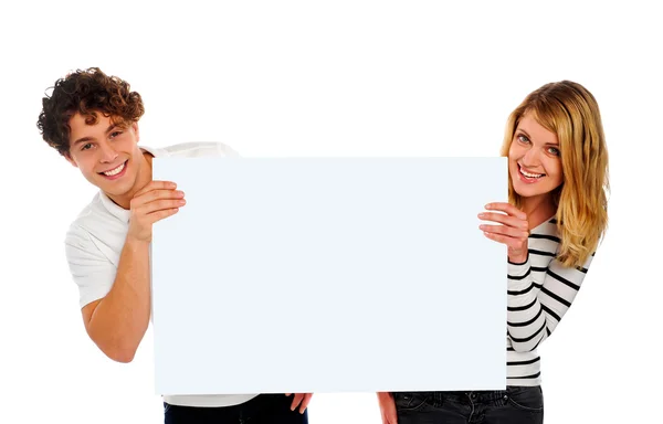 Casal sorrindo atraente segurando um quadro branco em branco — Fotografia de Stock