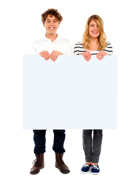Jovem casal de pé com placa branca — Fotografia de Stock