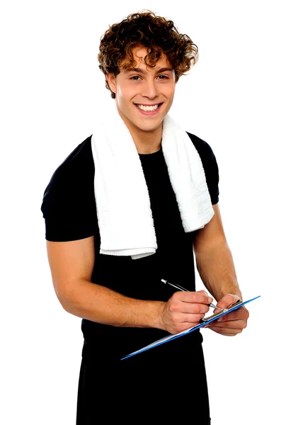 Smiling male trainer writing on clipboard — Stock Photo, Image