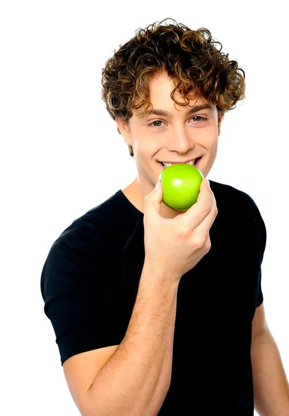 Young man eating fresh healthy green apple — Stock Photo, Image