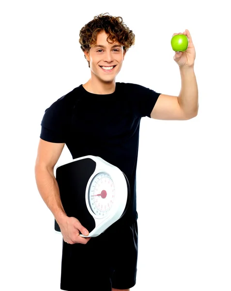 Fit guy with weighing scale and green apple — Stock Photo, Image