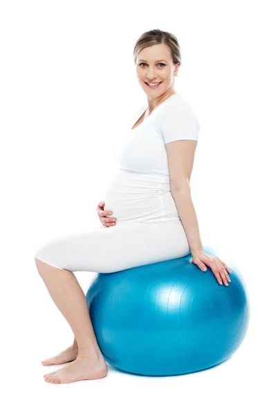 怀孕的女人坐在练习球 — 图库照片