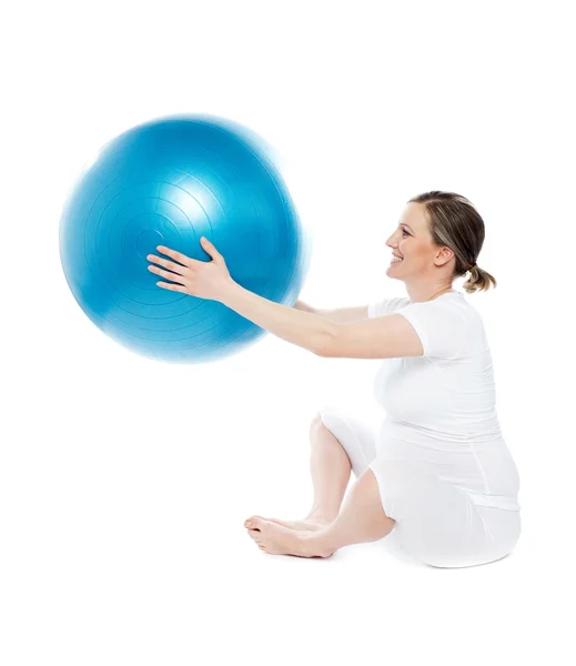 Беременная женщина сидит с мячом для упражнений — стоковое фото