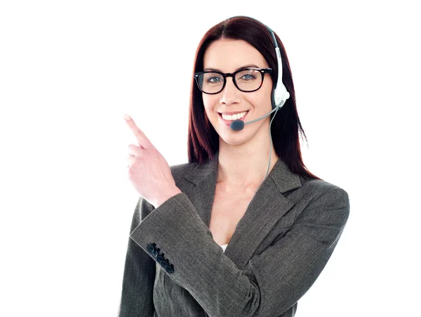 Operadora feminina com fone de ouvido apontando para algo — Fotografia de Stock