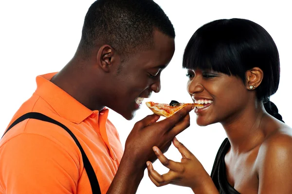Casal jovem compartilhando uma fatia de pizza — Fotografia de Stock