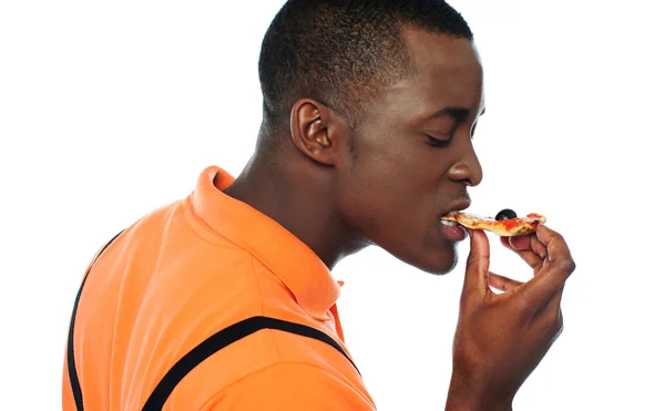 Young man eating a slice of pizza — Stock Photo, Image