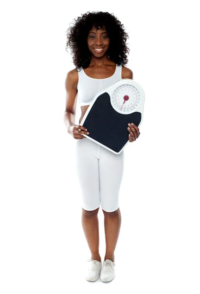 Fit female athlete holding weighing machine — Stock Photo, Image