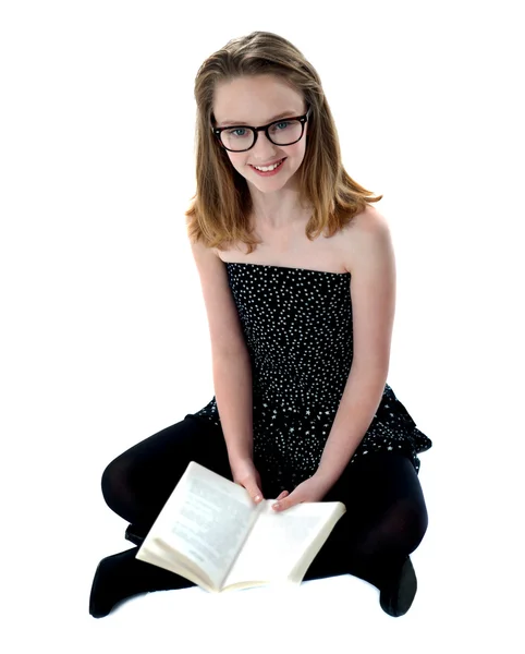 Scuola ragazza seduta su pavimento holding libro — Foto Stock