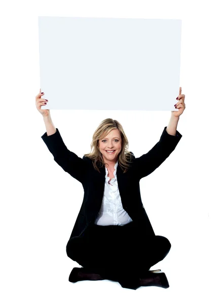 Seated female employee holding white clipboard over her head — Stock Photo, Image