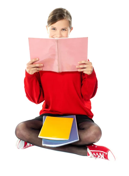 Meisje, zittend met boeken op haar schoot — Stockfoto