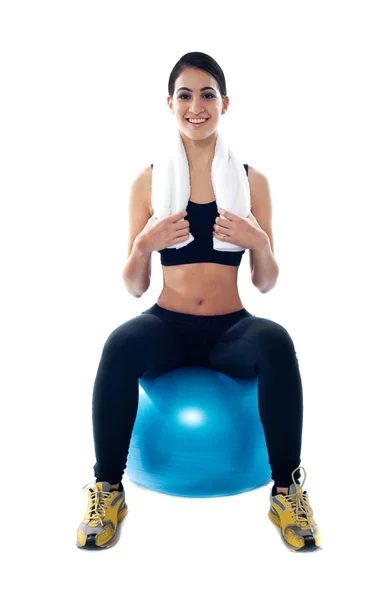 Athlète féminine attrayante assise sur une balle bleue — Photo