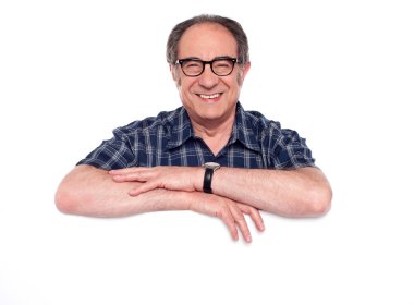 Smiling aged man posing with blank billboard