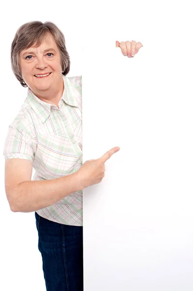 Causal senior lady pointing towards placard — Stock Photo, Image