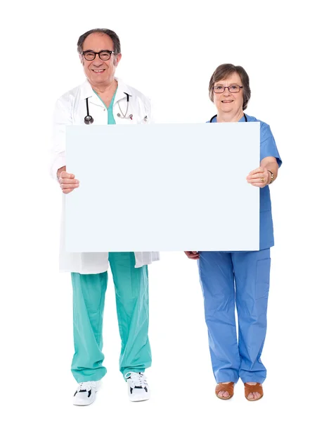Médicos idosos exibindo cartaz branco — Fotografia de Stock
