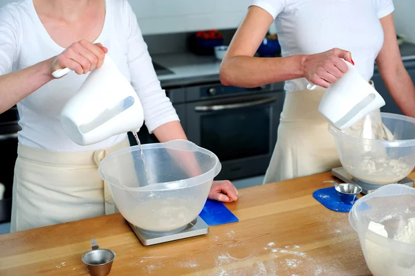 Kobiety strony wlewając wodę do miski mąkę — Zdjęcie stockowe
