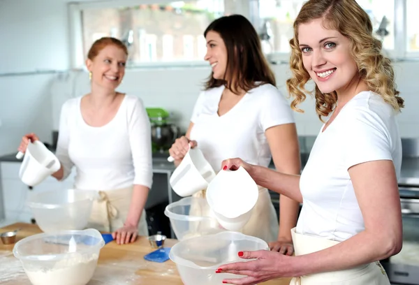 Female bakers pouring water into a plastic bowl — Stock Photo, Image