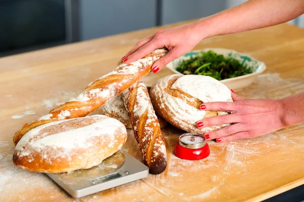 Руки женщин раскладывают багеты и хлеб — стоковое фото
