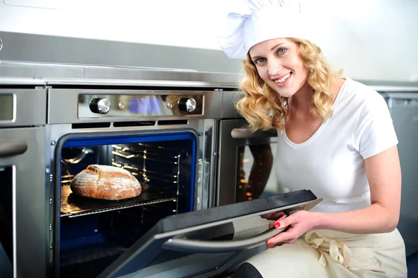 Pretty baker opening an oven door — Stock Photo, Image