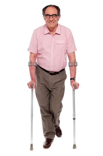 Lachende senior man lopen met twee krukken — Stockfoto