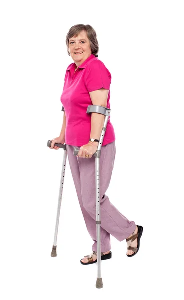 Lachende senior vrouw lopen met krukken — Stockfoto