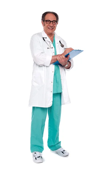 Médico envelhecido segurando prancheta. Tiro de comprimento total — Fotografia de Stock