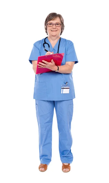 Starší ženský lékař psaní na schránky — Stock fotografie