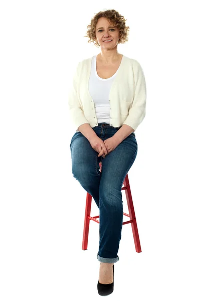 Confident smiling woman sitting on stool — Stock Photo, Image