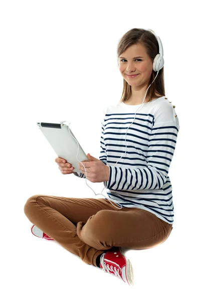 Menina sentada desfrutando de música no dispositivo portátil — Fotografia de Stock