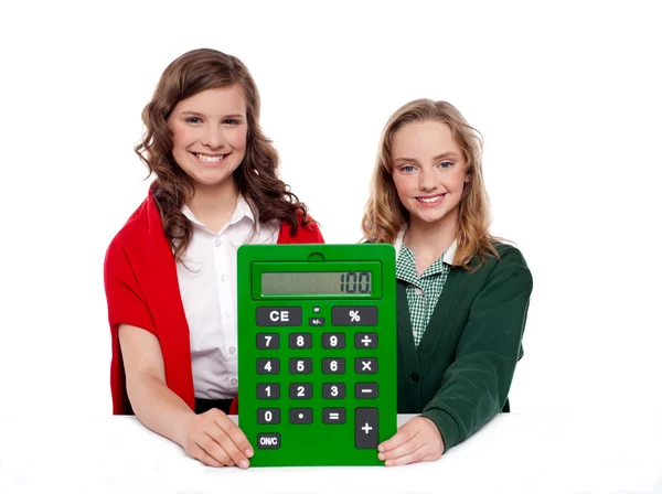 Дівчата показують великий зелений калькулятор на камеру — стокове фото