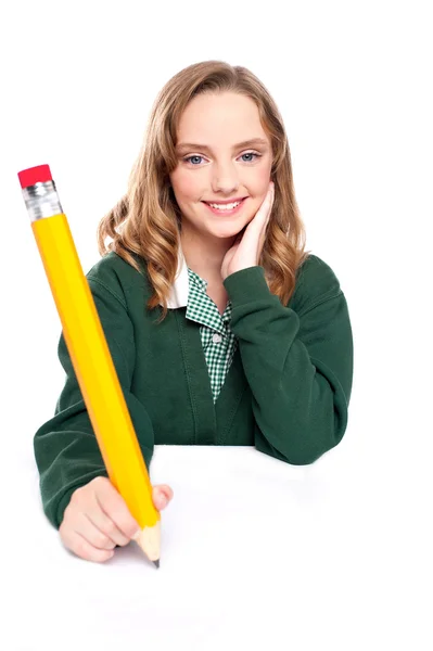 Młoda dziewczyna za pomocą ponad wielkości ołówka — Zdjęcie stockowe