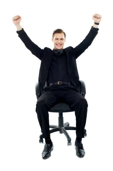 Возбужденный молодой человек сидит на стуле — стоковое фото