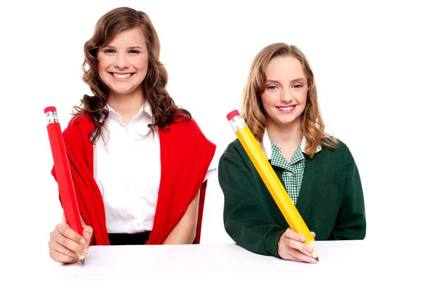 Female students writing with big pencil — Stock Photo, Image