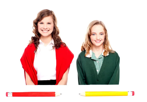 Große Bleistifte liegen vor zwei Schulmädchen — Stockfoto