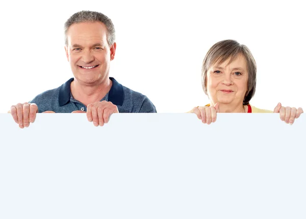 Old age couple holding blank banner ad — Stock Photo, Image