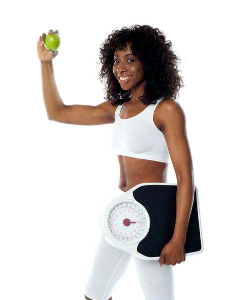 Athlete holding green apple and weighing machine — Stock Photo, Image