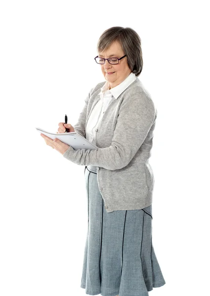Mujer mayor escribiendo en cuaderno espiral — Foto de Stock