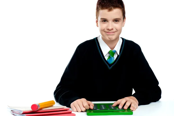 Smiling young boy using calculator — Stock Photo, Image