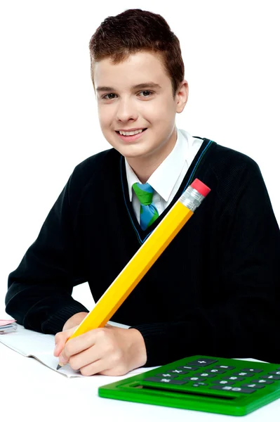 Мальчик делает уроки с калькулятором рядом с ним — стоковое фото