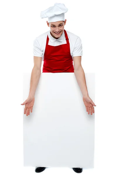 Guapo joven cocinero mostrando cartelera en blanco —  Fotos de Stock