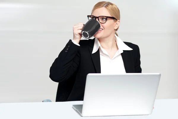 Affärskvinna njuter av kaffe på skrivbord — Stockfoto
