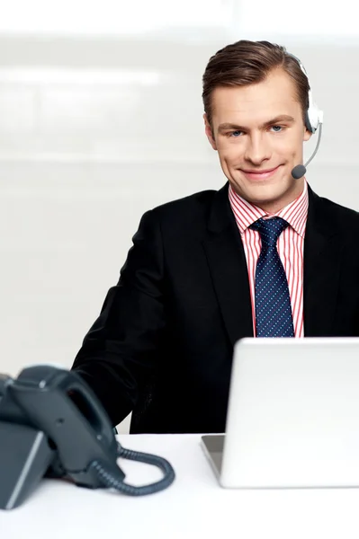 Executivo masculino usando fones de ouvido e sorrindo — Fotografia de Stock