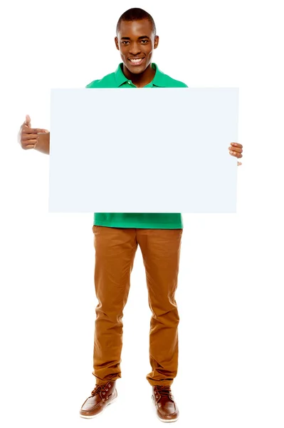Casual young guy pointing towards placard — Stock Photo, Image