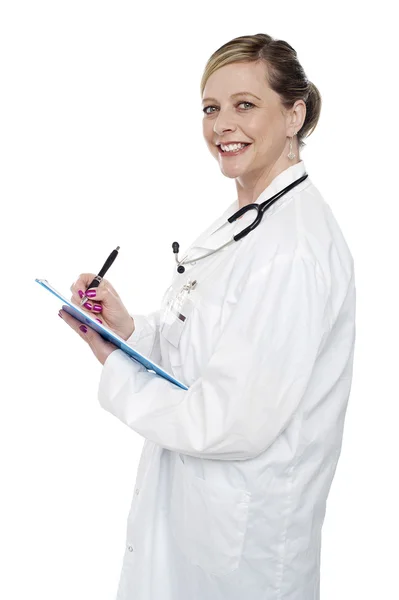 Uśmiechający się w wieku chirurg trzyma długopis i schowka — Zdjęcie stockowe