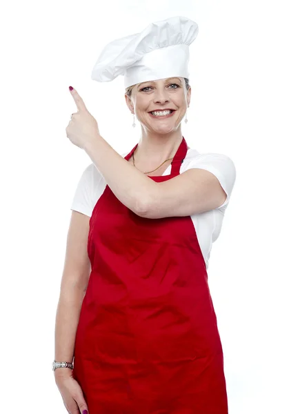 Sorrindo cozinheiro feminino apontando para longe — Fotografia de Stock